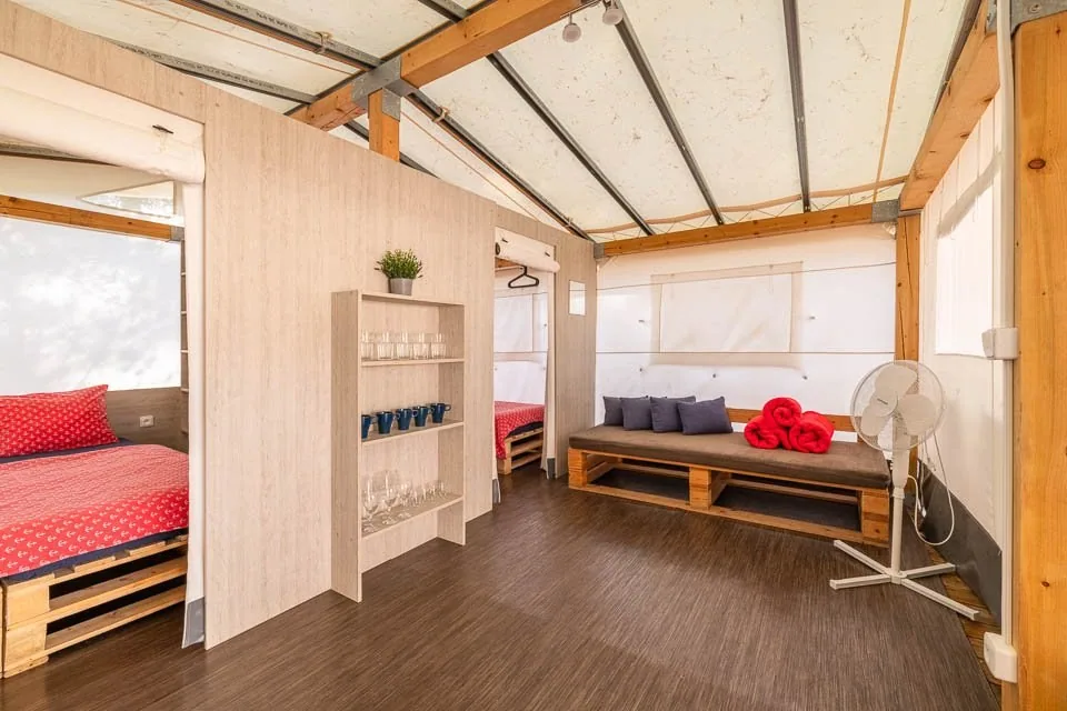 Sofa and separate sleeping areas inside a Glamping CLASSIC tent at Camp Čikat