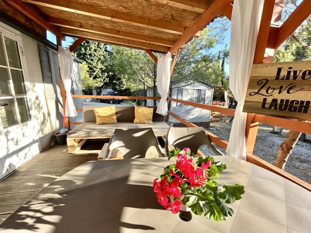 Sofa and coffee table on the shaded covered terrace of a mobile home at Camp Adriatic